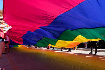 volunteers wawing a giant rainbow flag in a pride parade