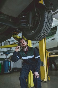 Male mechanic examining a car with torch