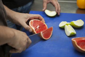 Hands of a grapefruit cutting chef