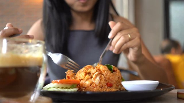 Asian women eat fried rice happily in restaurants.