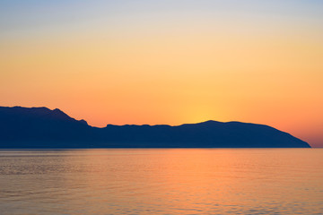 Naklejka premium Red sunset over Greek islands in calm sea 
