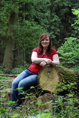 Junge Frau sitzend lächelnd im Wald