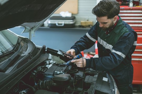 Mechanic taking picture of car engine with mobile phone