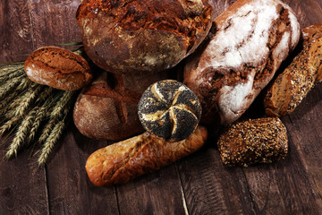 Different kinds of bread and bread rolls on board from above. Kitchen or bakery