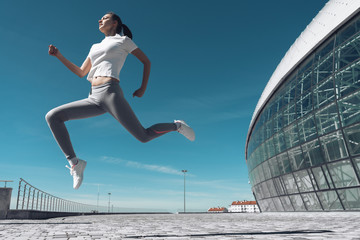active young girl jumping outdoors, warming up and doing exercises