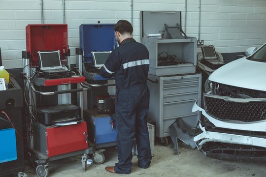 Rear view of mechanic using laptop in garage