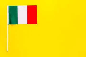 Italian flag concept. small flag on yellow background top view copy space