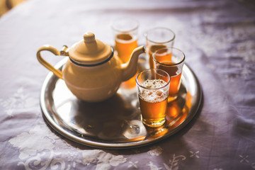 close up of a moroccan tea pot with glasses on a silver plate