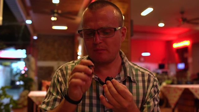 A Man Eating A Fried Scorpion In A Thai Restaurant