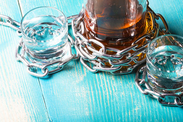 a bottle of rum and two glasses next wrapped with a metal chain