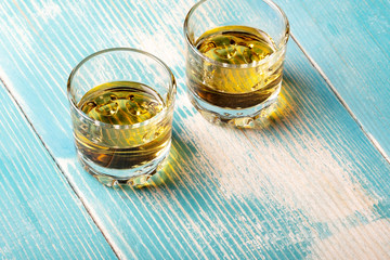 two glasses of whiskey on a wooden table blue