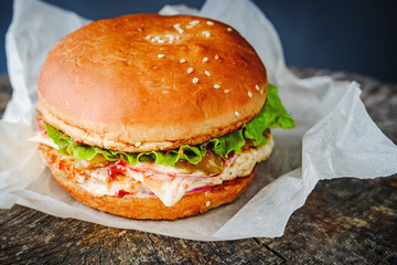 appetizing homemade burger in wrapping paper on wooden table