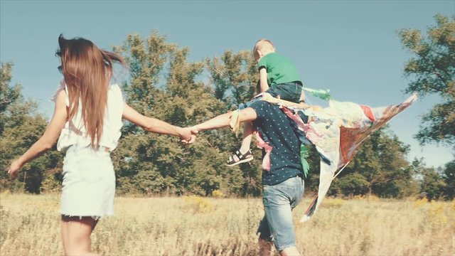 Happy family, mom, dad and son are walking in nature, launching an air snake. Stock footage.