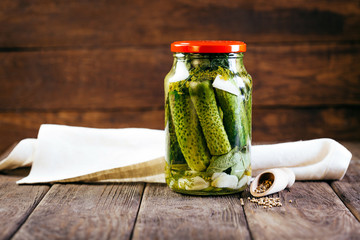 canned cucumbers in a jar on a wooden background, harvesting vegetables, pickles - Powered by Adobe
