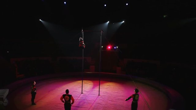 Acrobat performs exercises on the bar in the circus arena