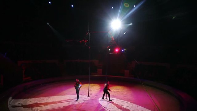 Acrobat performs exercises on the bar in the circus arena