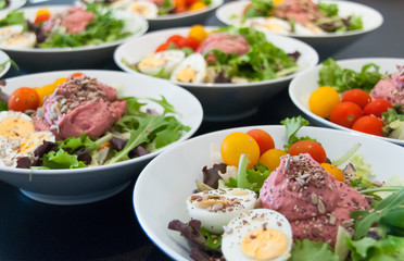 White bowls with mix salad of lettuce, cherry tomatoes, boileg eggs, sunflower seeds and pink sauce ready to eat. Vegetarian food, healthy eating concept