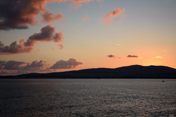 Obraz premium Sunset over the sea. The Sun sets behind the mountains