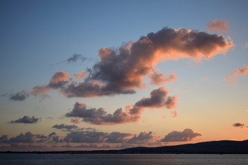 Naklejka na ściany i meble Clouds over the sea illuminated by the sun
