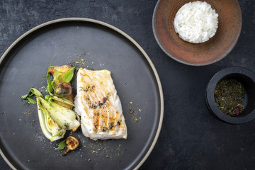 Modern Thai fried cod fish filet with bok choi and rice as top view on a plate