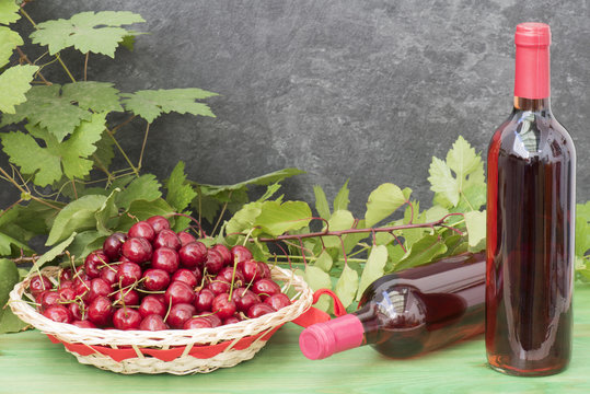 Dos botellas de licor de guindas y una cesta con la fruta fresca