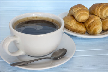Coffee and croissants in a plate on a blue background