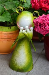 Dekoration Metallfrosch lustig zwischen Blumen auf einem Balkon