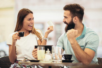 Beautiful couple having coffee on a date, using digital tablet and credit card for online shopping