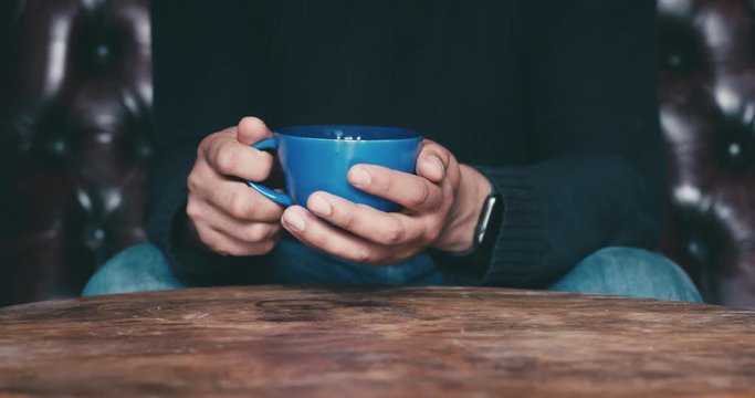 Young man with cup of coffee on sofa