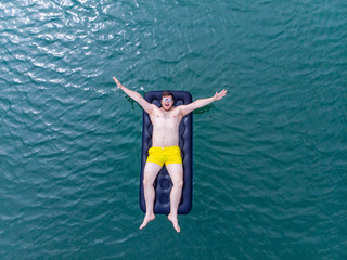 man on mattress in blue water. summer time concept