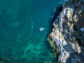 directly above view of man swimming in the water mattress near the rock on a summer vacation