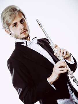 Male flutist wearing tailcoat holds flute
