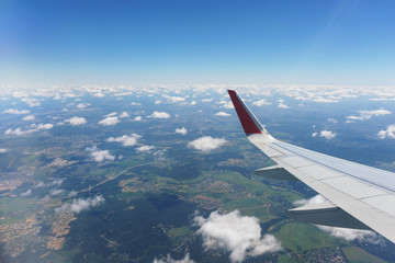 Fototapeta premium Aerial view of the small city, ground and clouds from the aircraft during the flight.