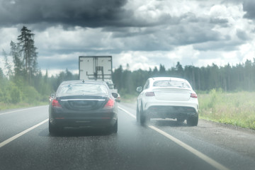 Fototapeta na wymiar The car goes around the traffic jam on the side of the road. Violation of traffic rules. Lots of water drops. Dark stormy sky with clouds