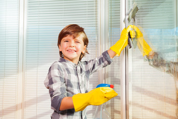 Little boy washing windows using spray bottle