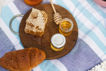 bottle with honey, bagel and honeycomb on a wooden plate