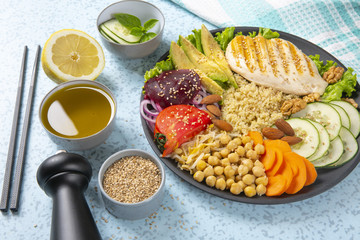 Bowl of Buddha, The concept of a healthy diet: grilled chicken, avocado, chickpeas, kinua, carrots, tomatoes, nuts. Balanced food. Top view. Copy space.