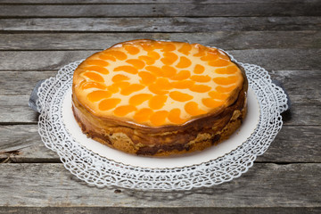 Schmandkuchen mit Mandarinen auf grauem Holzuntergrund