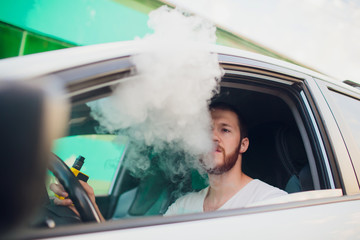 Man vaping e-cigarette with e-liquid, close-up, breathes out large cloud of steam or vapor. Vape...