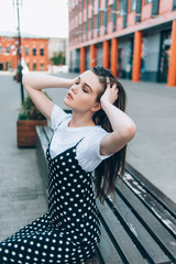 A beautiful girl in a long black sarafan walks down the street. loft style.