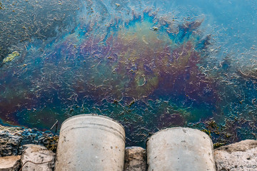Sewer pipes at shore, stain of oil or fuel on water surface, nature pollution by toxic chemicals,...