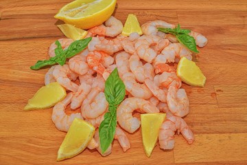 Cooked and peeled prawns with slices of lemon and leaves of basil on chopping board. Food photography. Healthy food. Bio recipe