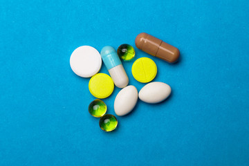 Colored pills, tablets and capsules on a blue background. Medicine and health.