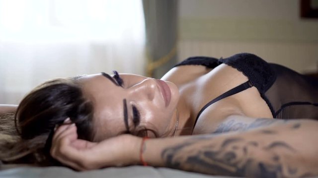 Passionate beautiful model lying on the bed in the hotel and posing for photos