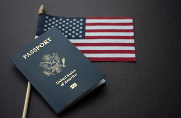 Flag of United States (American) next to Passport of USA on Black surface.