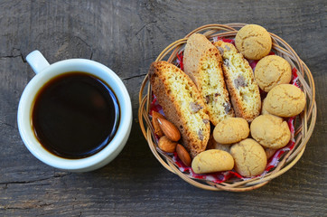 Traditional italian cantuccini and amaretti cookies with almond and cup of coffee on old wooden background.Selective focus.