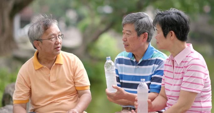 Elderly friends talk together at outdoor park