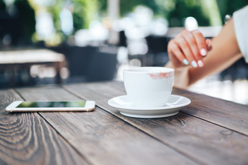 White cup of coffee with lipstick. On the table a cup of coffee and a telephone