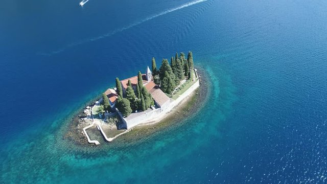 Tilting drone shot of small natural island with monastery (Sveti Dorde) in the Bay of Kotor in Montenegro