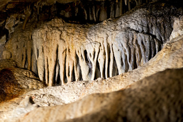 Fototapeta na wymiar Stalactites and stalagmites inside natural limestone cave. Natural formations.